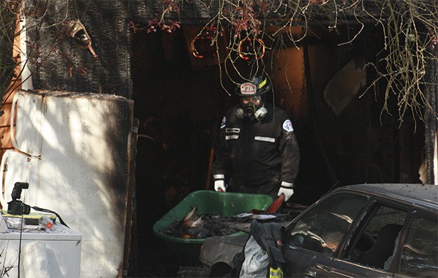 A Bellevue firefighter removes belongings burned in a duplex fire early Monday morning