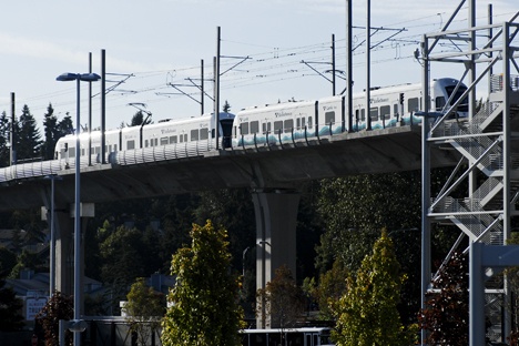 A light rail train moves on elevated tracks along the Central Link line from Seattle to Tukwila.