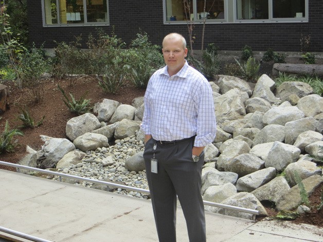 Kyle McLeod stands in front of one of the rain gardens. The large rocks act as an overflow protection