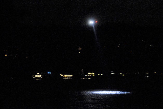 A U.S. Coast Guard helicopter provides aerial support into the night during the search for a reported missing kayaker in the East Channel of Lake Washington off Mercer Island on Saturday.