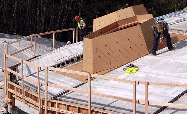 Construction crew members work on the roof of the Bellevue Youth Theatre