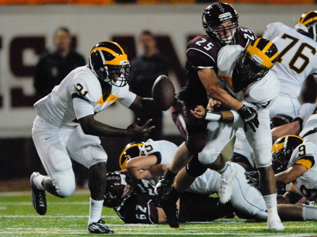 Wolverine QB Tyler Hasty (1) just gets the pitch to RB Myles Jack (21) as he is wrapped up by Islander LB Brian Rauzi (25) during the second half at Mercer Island on Friday. Bellevue won 43-28.