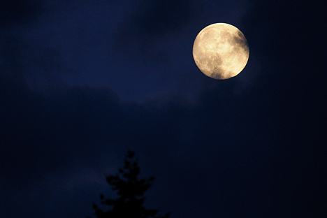 The moon shines through the clouds as it rises over Bellevue on Friday night. A full moon will occur at 11:11 p.m. on Saturday.