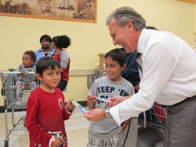 Bellevue dentist Dr. Mark DiRe tooth brushes from a dental kit to students as part of the Assistance League of the Eastside’s Operation School Bell. More than 2