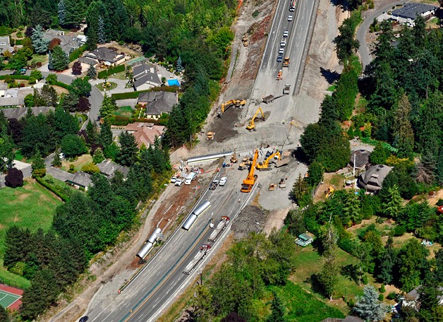 Workers carve a nearly 20-foot-deep trench across all lanes to install a fish-passable culvert beneath SR 520 east of 84th Avenue Northeast.