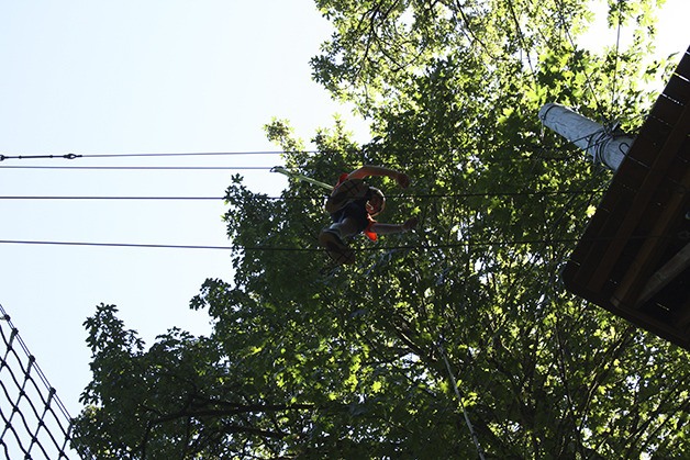 A youngster balances on a pair of suspended cables above the forest floor at the Challenge Course.