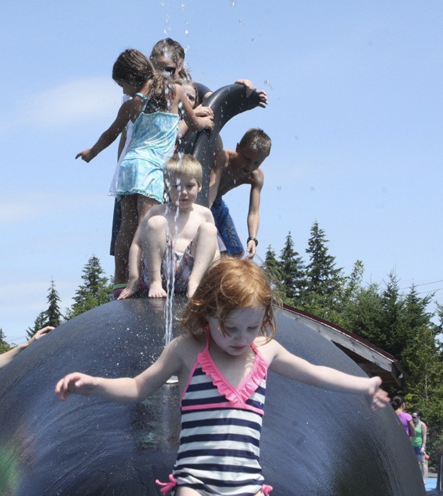 A spouting orca acts as a water slide for children.