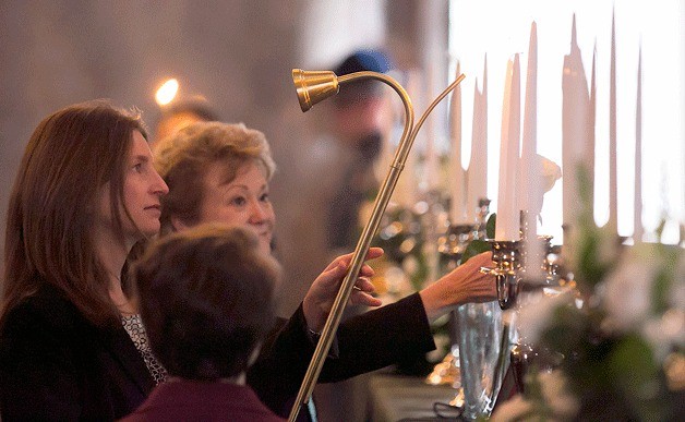 State Reps. Tana Senn (left) and Judy Clibborn light a candle at a Feb. 18 memorial for elected officials who have passed away in the past two years. Clibborn and Senn