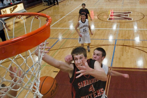 Totem's Steve Perkins (4) is fouled on a drive to the basket by Islander's Brian Miller during the second half of a game at Mercer Island on Tuesday. Sammamish rallied late to win 52-47 on the road.