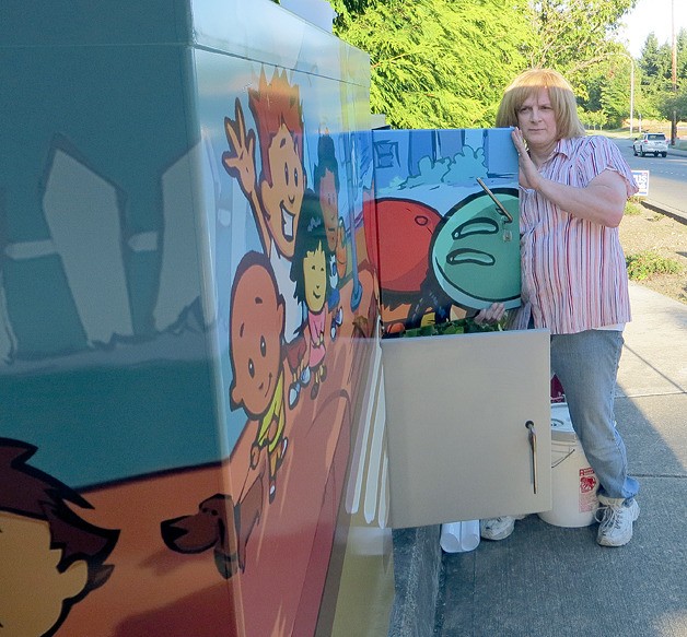 Tammie Heber of Morup Signs of Bellevue finishes putting artwork on a utility box in the Sherwood Forest neighborhood on Thursday