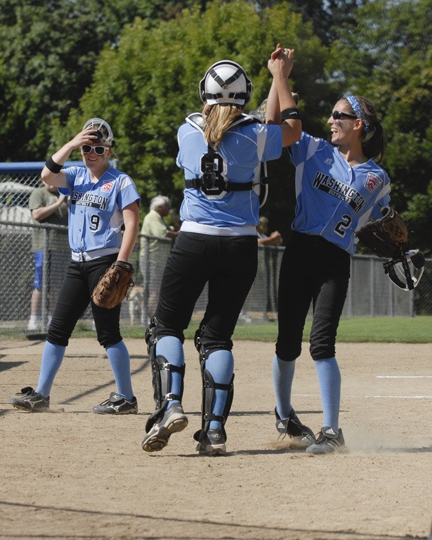 Kathryn Wood (2) and Claire McCarthy (8) celebrate as teammate Brooke Baumgartner looks on during the Junior Softball World Series. The hosts from District 9 will head into Thursday's game needing a win over unbeaten Central to earn a spot in the championship semi-finals.