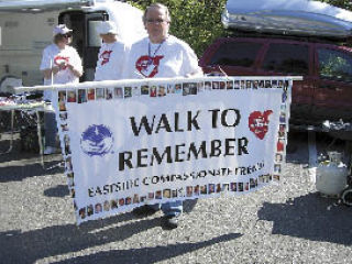 Dale Gunnoe holds a banner at the Walk to Remember event. In the background are Jane and Elmer Peters.